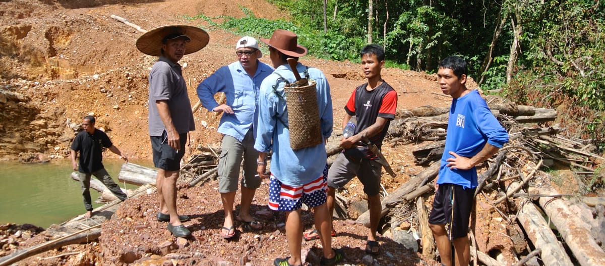 Indigene stehen auf einer Piste, die Holzfäller illegal in Sarawak angelegt haben