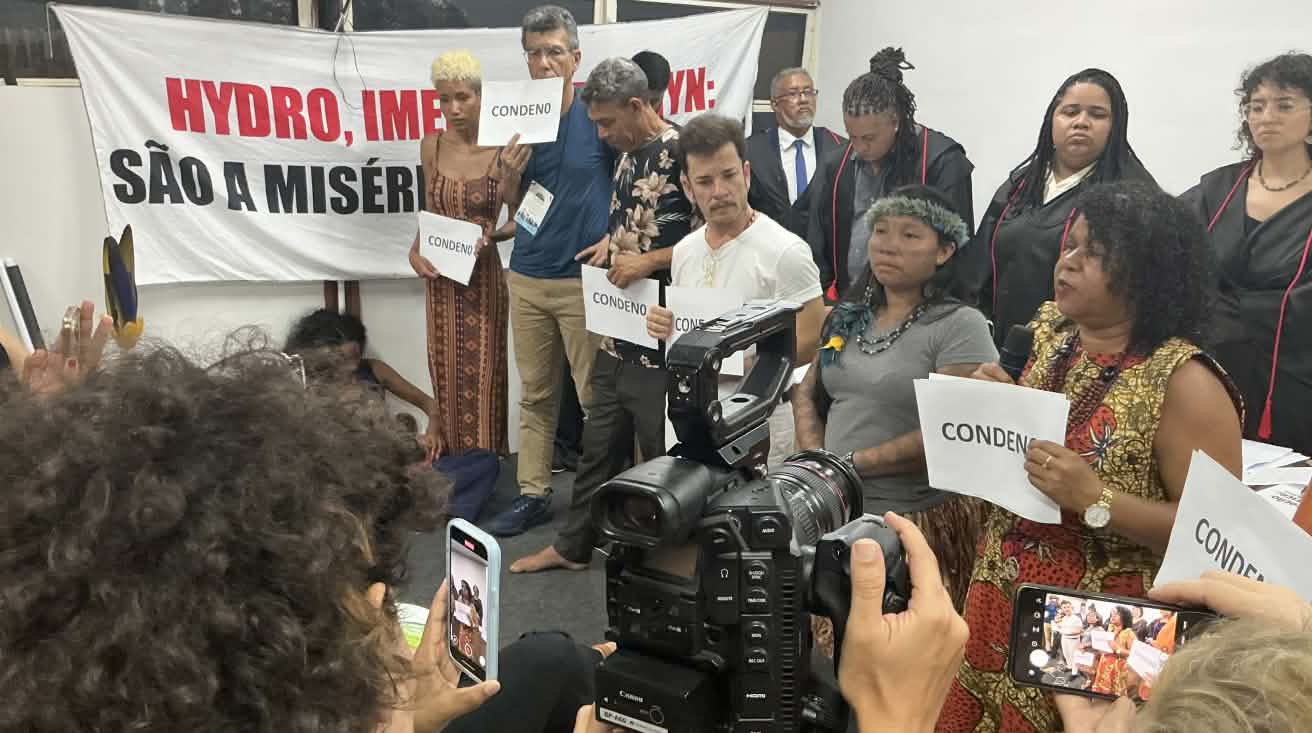 Eine Gruppe von zehn Personen, die das symbolische Gerichtsverfahren durchgeführt hat, wird mit einer Fotokamera und Handys gefilmt