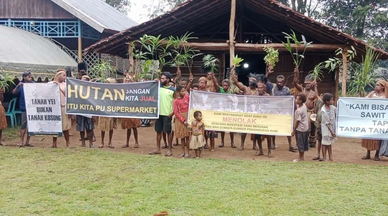 Demo der indigenen Yei mit Bannern vor einem Haus