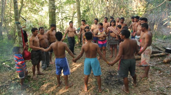 Indigene Ka'apor  - Kinder, Frauen und Männer - fassen sich an den Händen und bilden einen Kreis im Regenwald