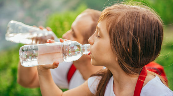 Ein junges Mädchen trinkt Wasser aus einer PET-Einwegflasche