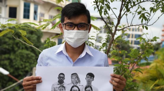 Junger Mann hält Plakat mit den 6 inhaftierten Aktivisten hoch