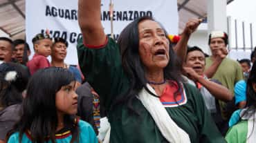 Indigene Einwohner, Frauen, Kinder und Männer protestieren vor einem Banner