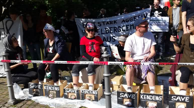Protest vor der Stadthalle Heidelberg: Aktivisten mit einbetonierten Füßen Protest gegen HeidelbergCement: Aktivisten betonieren ihre Füße ein
