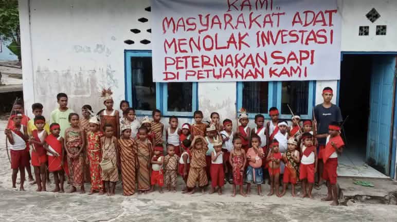 Kinder vor Schule mit Banner "Wir Indigenen lehnen Investitionen in Rinderzucht auf unserem Indigenenland ab"