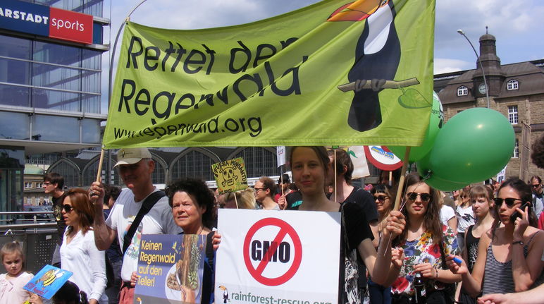 Die hamburger Regionalgruppe  von Rettet den Regenwald hält auf einer Demo gegen Monsanto ein Banner und Plakate in die Höhe.