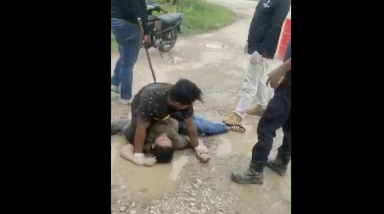 Szene aus einem Video: hinter dem Opfer steht einer der Täter mit einem Schlagstock Ein Dorfbewohner wird von Plantagen-Mitarbeiter zusammengeschlagen