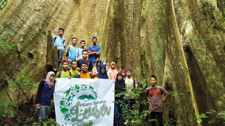 „Wir sind Freunde von Leuser“ steht auf dem Plakat der von Rudi Putra ins Leben gerufenen Jugendbewegung. Der Urwaldriese in ihrem Rücken zeigt, was es zu schützen gilt. Er wächst im Leuser Nationalpark Widerstand im Leuser Nationalpark