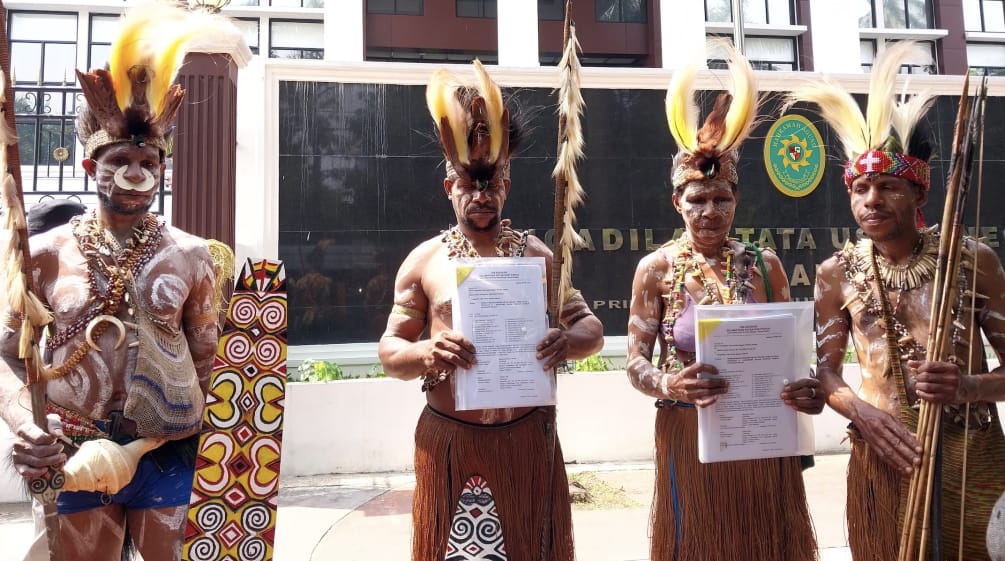 vier Papua in traditioneller Kleidung vor Gerichtsgebäude
