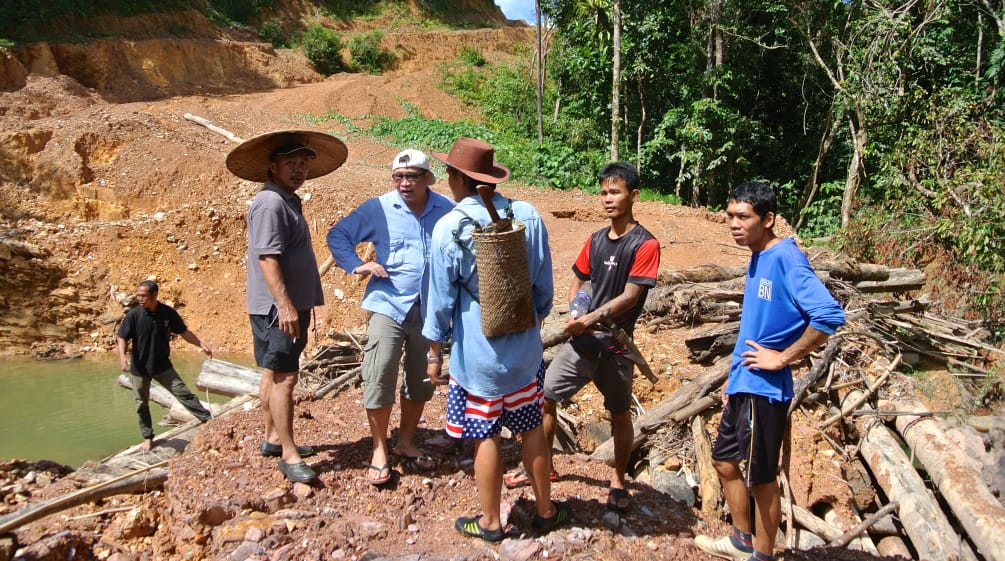 Indigene stehen auf einer Piste, die Holzfäller illegal in Sarawak angelegt haben