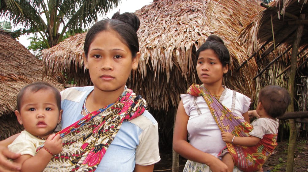 Die indigenen Pala'wan, Ureinwohner der Insel, brauchen zum Überleben ihren Wald, keine Plantagen 2 Frauen mit ihren Kindern vor strohgedeckten Häusern