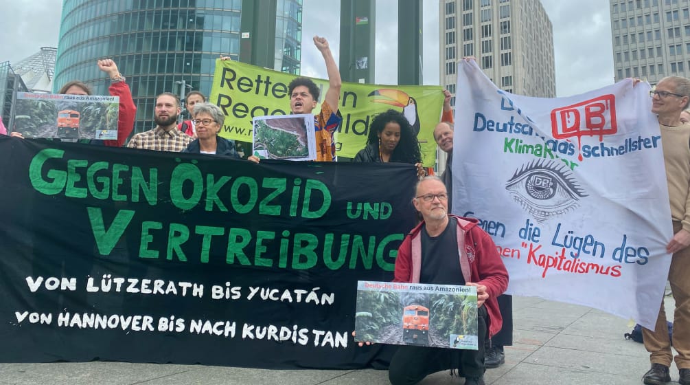 Demonstration vor der DB-Zentrale auf dem Potsdamer Platz in Berlin Ende Mai 2024 Eine Gruppe von Personen protestiert mit grossen farbigen Bannern vor drei Bürohochhäusern