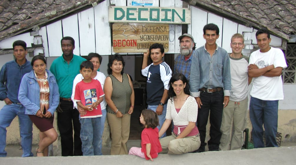 Gruppe von Personen von DECOIN und Rettet den Regenwald vor einer Holzhütte mit der Aufschrift DECOIN