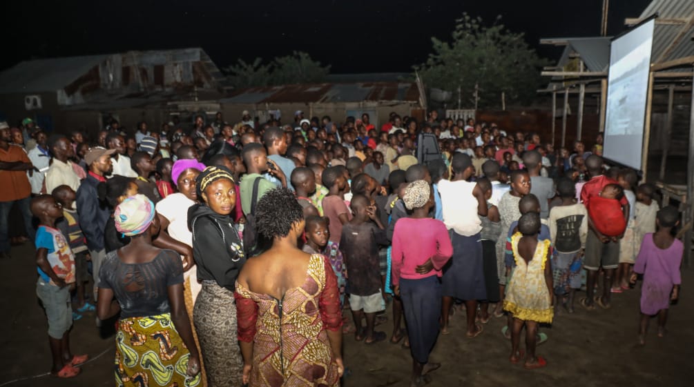 Auf einer großen Leinwand wird der Film "La malédiction du pétrole au Nigeria" gezeigt Filmvorführung Fluch des Erdöls im Dorf Vitshumbi (Virunga),