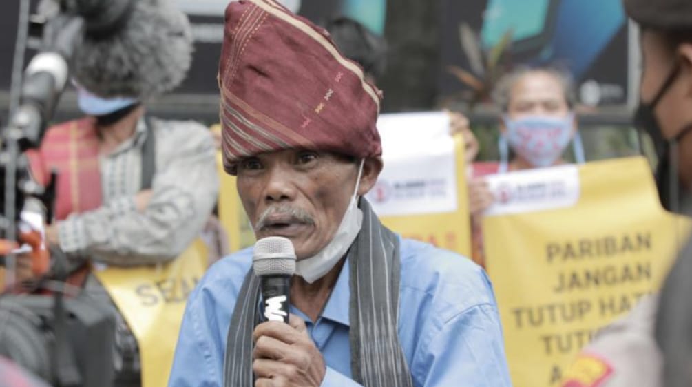 ein Batak-Mann mit typischer Kopfbedeckung und Mikrophon