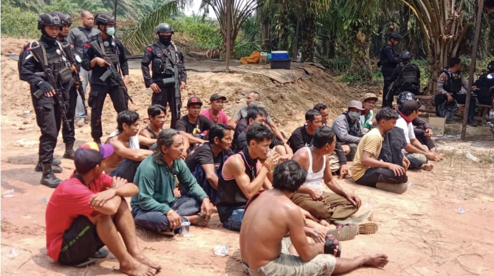 Widerstand gegen Landraub für Palmöl endet blutig oder im Gefängnis: verhaftete Dayak auf der Plantage der Best Group verhaftetete Dayak sitzen auf dem Boden, dahinter bewaffnete Polizisten