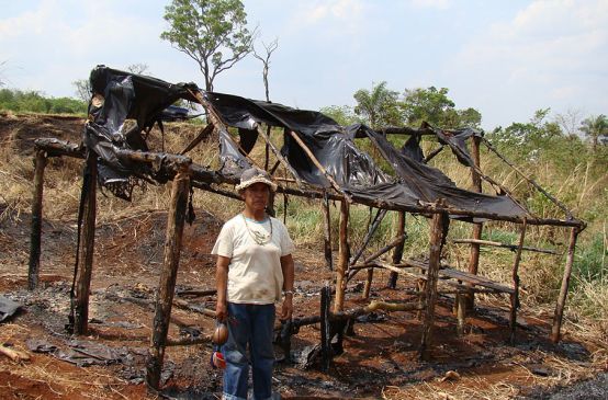 Guarani-Kaiowá vor zerstörter Hütte