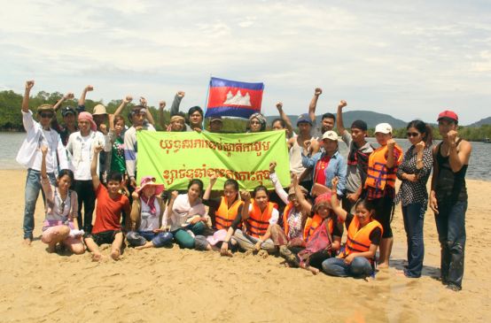 Aktivisten mit Banner in der Hand protestieren am Strand