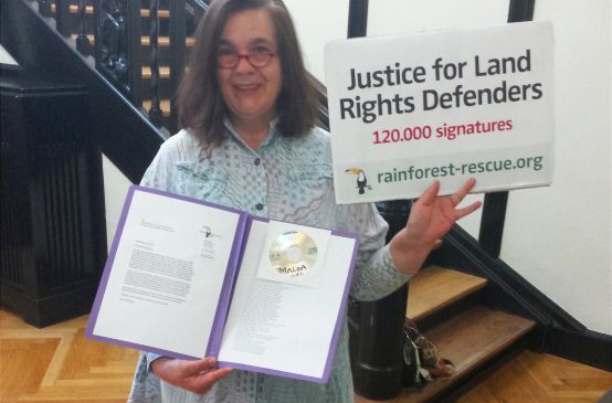 Eine Aktivistin von Rettet den Regenwald hält in der Botschaft von Sierra Leone Petition und Übergabeplakat in die Höhe.