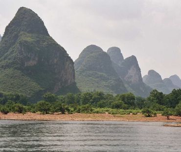 Für den Abbau von Kalkgestein werden ökologisch wertvolle Karstgebiete zerstört (Foto: Karstlandschaft in China). Karstgebirge an einem Fluss
