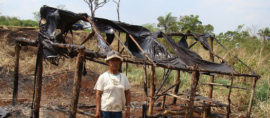 Guarani-Kaiowá vor zerstörter Hütte