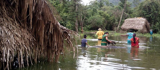 Menschen waten zwischen zwei Häusern durch das hüfttiefe Wasser