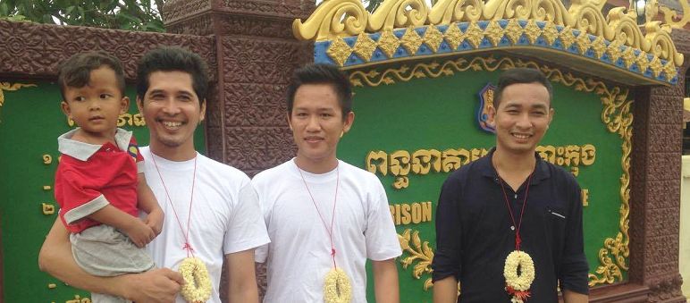 Sim Somnang, Try Sovikea und San Mala (von links) nach ihrer Freilassung 3 Aktivivisten, einer mit Sohn auf dem Arm, stehen nach ihrer Freilassung vor dem Gefängnis