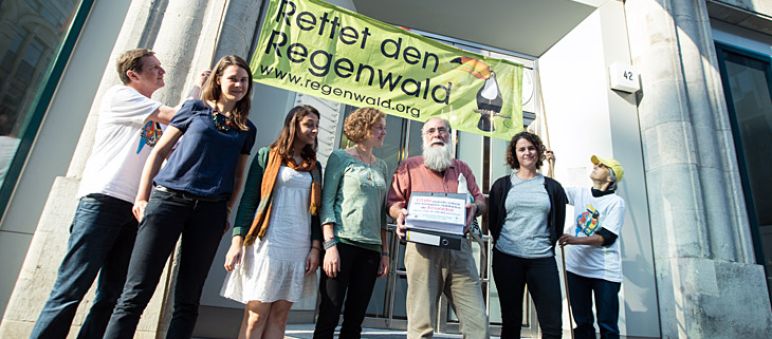 Chile soll Ecuadors Regenwälder erhalten, fordern Carlos Zorilla und deutsche Umweltschützer vor der Botschaft des Landes in Berlin (Foto: Christine Denck) Aktivisten von Rettet den Regenwald e.V. und Intag e.V. demonstrieren vor der Botschaft von Chile. Carlos Zorilla von DECOIN aus Ecuador trägt die Aktenordner mit den Dokumenten und Unterschriften.