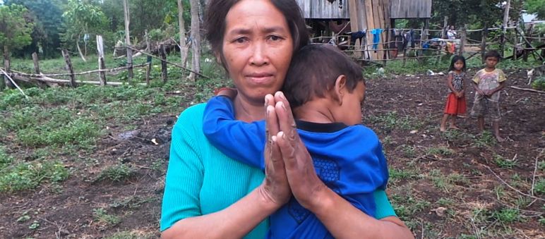 „Wir hatten Mangos, Cashews, Reis, Melonen – alles ist zerstört. Jetzt haben wir nur noch ein paar Quadratmeter Land für Gemüse“, sagt Yoeung Kheung Eine Frau mit Kind auf dem Arm steht vor ihrer provisorisch aufgebauten Hütte. Von ihrem eigenen Land wurde sie vertrieben