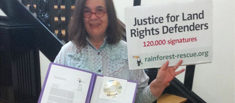 Rettet den Regenwald übergibt 120.000 Unterschriften zur Unterstützung der Landrechtskämpfer in SIerra Leone. Eine Aktivistin von Rettet den Regenwald hält in der Botschaft von Sierra Leone Petition und Übergabeplakat in die Höhe.