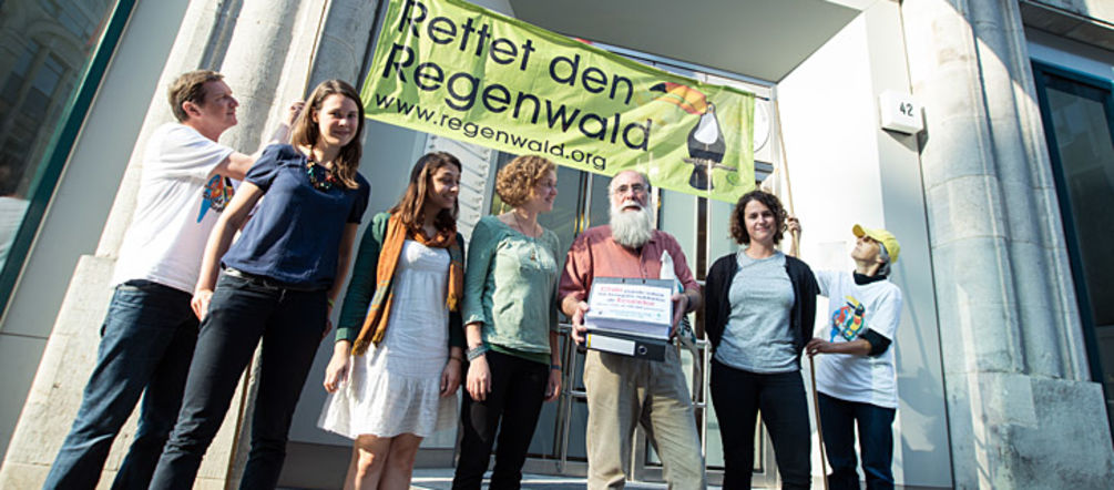 Chile soll Ecuadors Regenwälder erhalten, fordern Carlos Zorilla und deutsche Umweltschützer vor der Botschaft des Landes in Berlin (Foto: Christine Denck) Aktivisten von Rettet den Regenwald e.V. und Intag e.V. demonstrieren vor der Botschaft von Chile. Carlos Zorilla von DECOIN aus Ecuador trägt die Aktenordner mit den Dokumenten und Unterschriften.
