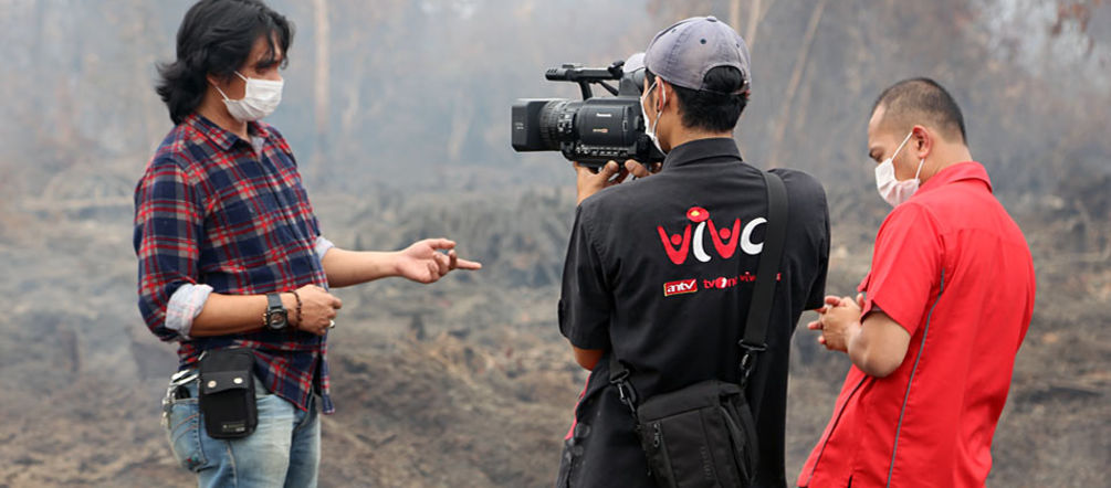 „1.000 Hektar Torfregenwald wurden hier verbrannt“, so Umwelt-Aktivist Feri Irawan im TV-Interview. „Doch noch können wir den größten Teil des Waldes retten.“ Ein Mann wird vor brennendem Regenwald interviewt