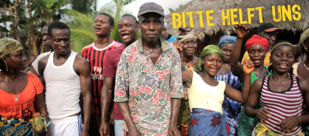 Der Volksstamm der Jogbahn kämpft um sein Land (Foto: Jason Taylor for FoE International 2014) In einem Dorf demonstrieren zahlreiche Afrikaner. Sie haben Trommeln dabei.