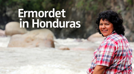 Die Umweltaktivistin Berta Cáceres sitzt auf einem Stein am Fluss und blickt über ihre Schulter in die Kamera