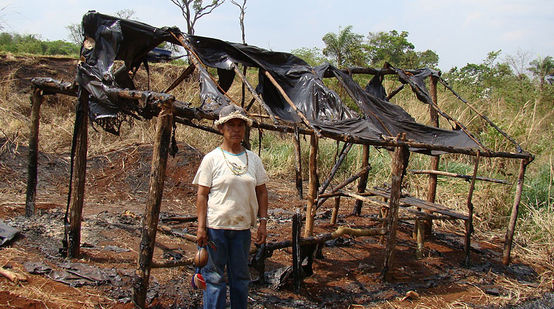 Guarani-Kaiowá vor zerstörter Hütte