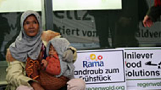Frau protestiert mit Kind im Arm und Schildern gegen Unilever