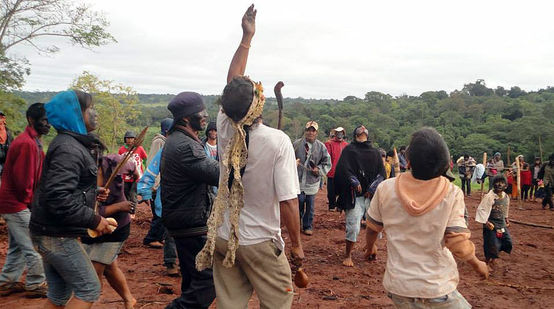 Die Eingeborenen des Avá Guaraní Stammes tanzen auf den Ruinen ihres zerstörten Tempels