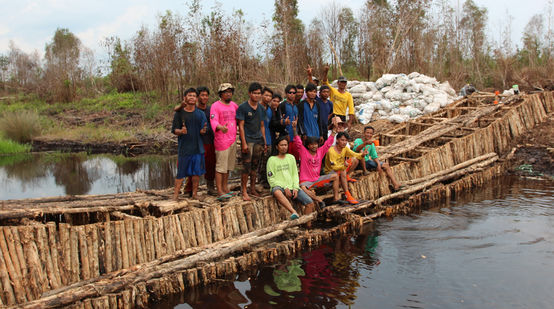 Umweltschützer stehen auf einem Damm, den sie aus Holz gebaut haben, um einen Kanal zu blockieren