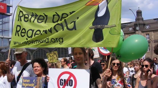 Die hamburger Regionalgruppe von Rettet den Regenwald hält auf einer Demo gegen Monsanto ein Banner und Plakate in die Höhe.