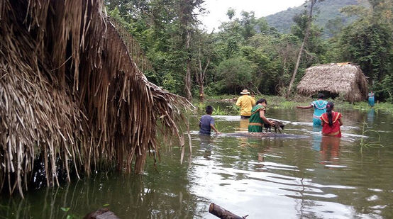 Menschen waten zwischen zwei Häusern durch das hüfttiefe Wasser