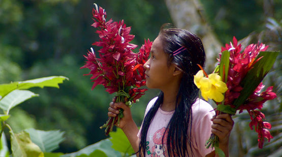Ein Kichwa-Mädchen mit Blumen in den Händen