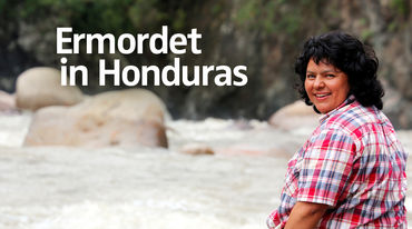 Die Umweltaktivistin Berta Cáceres sitzt auf einem Stein am Fluss und blickt über ihre Schulter in die Kamera