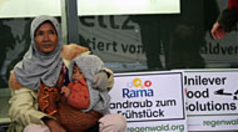 Proteste vor Unilever-Haus Frau protestiert mit Kind im Arm und Schildern gegen Unilever