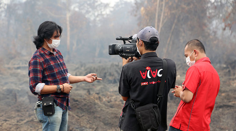„1.000 Hektar Torfregenwald wurden hier verbrannt“, so Umwelt-Aktivist Feri Irawan im TV-Interview. „Doch noch können wir den größten Teil des Waldes retten.“ Ein Mann wird vor brennendem Regenwald interviewt