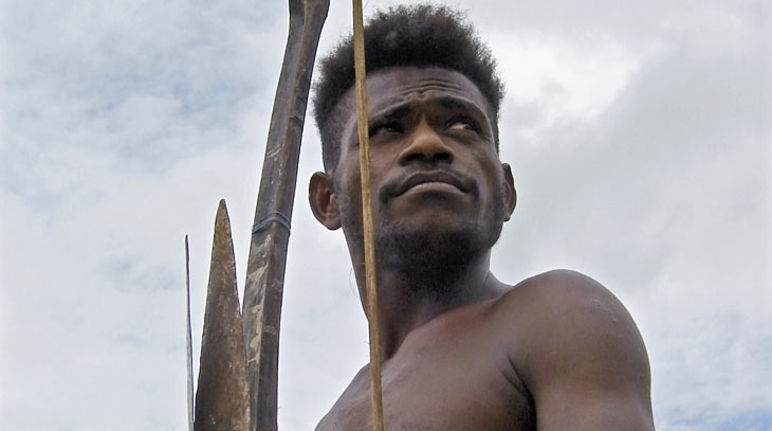 Ein junger papua mit einem Bogen blickt in die Ferne