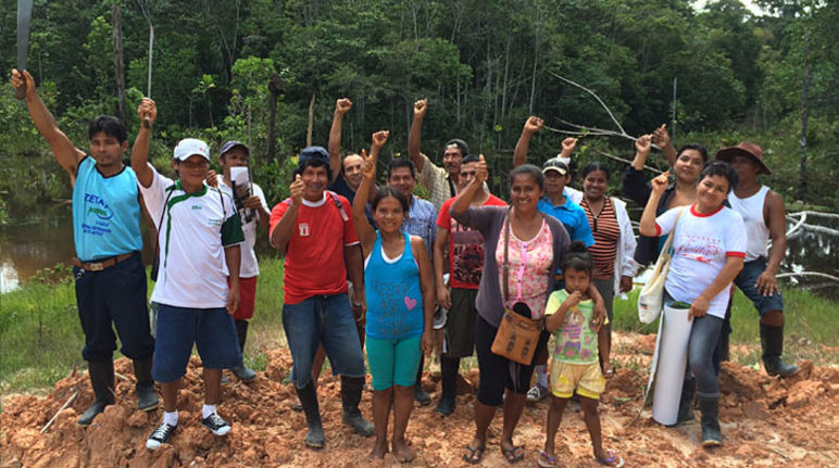 Auf einem Lehmhügel steht eine Gruppe von Peruaner im Urwald und freut sich