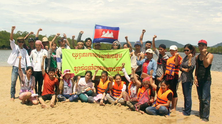 Aktivisten mit Banner in der Hand protestieren am Strand
