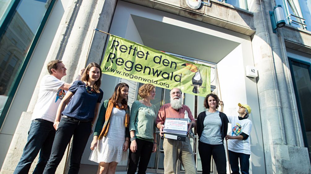 Chile soll Ecuadors Regenwälder erhalten, fordern Carlos Zorilla und deutsche Umweltschützer vor der Botschaft des Landes in Berlin (Foto: Christine Denck) Aktivisten von Rettet den Regenwald e.V. und Intag e.V. demonstrieren vor der Botschaft von Chile. Carlos Zorilla von DECOIN aus Ecuador trägt die Aktenordner mit den Dokumenten und Unterschriften.