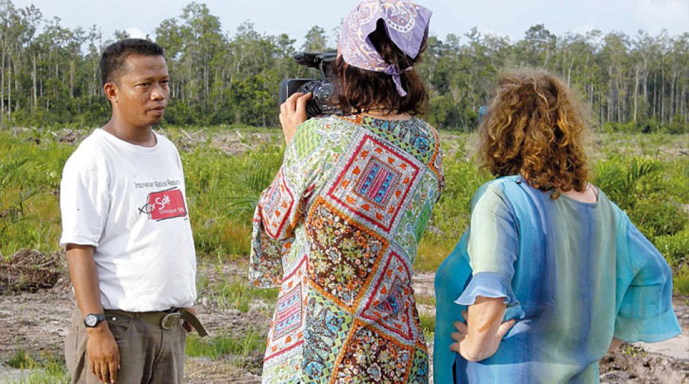 Dreharbeiten des Filmteams im Regenwald Der indonesische Umweltschützer Nordin wird von zwei Journalistinnen vor einer abgeholzten Fläche im Regenwald gefilmt
