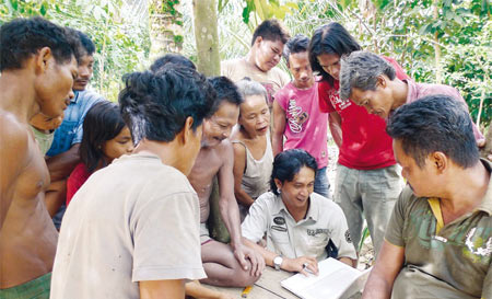 Feri Irawan hält für die An­klagen jede Urwaldzerstörung fest – hier zeigt er den betroffenen Waldbewohnern bei Bungku die Aufnahmen